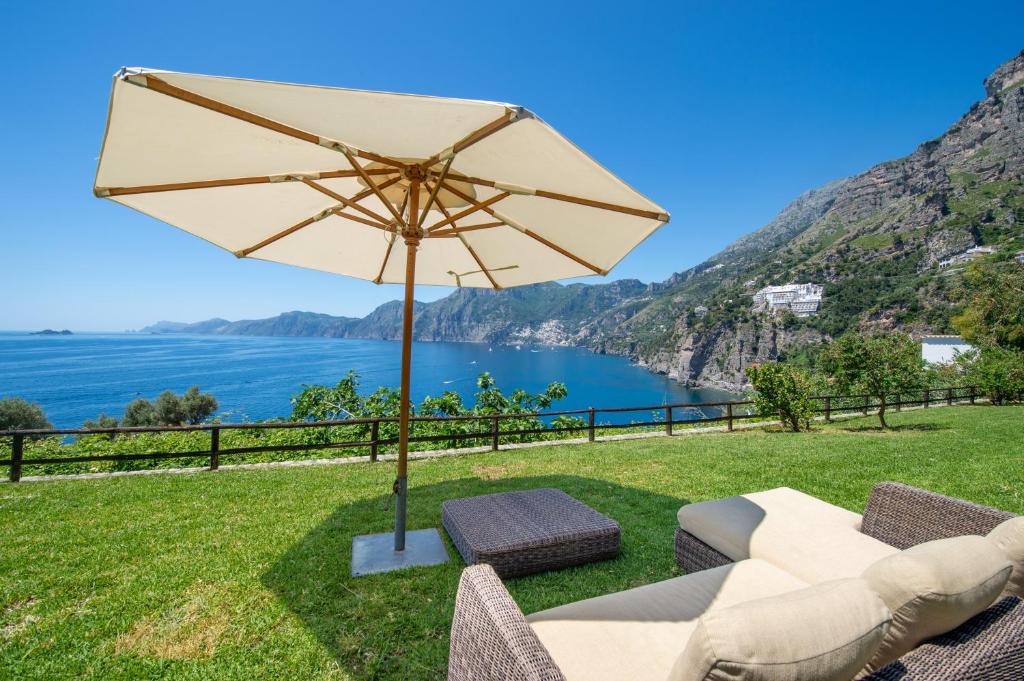 un patio avec une table, des chaises et un parasol dans l'établissement Seventh Heaven Praiano, à Praiano