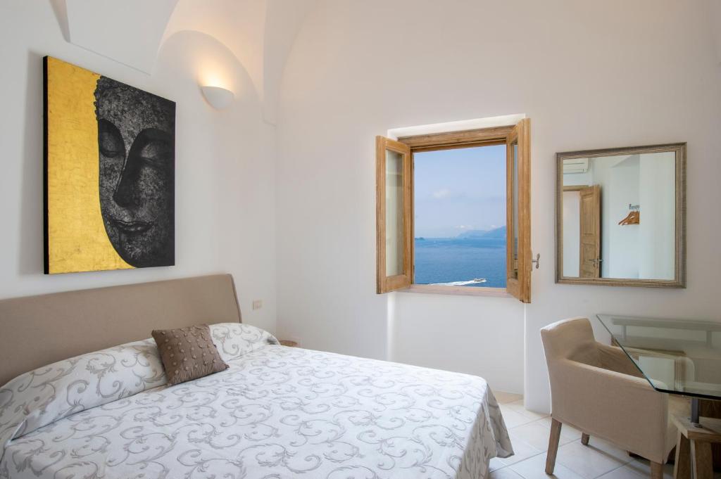une chambre avec un lit et un bureau et deux fenêtres dans l'établissement Seventh Heaven Praiano, à Praiano
