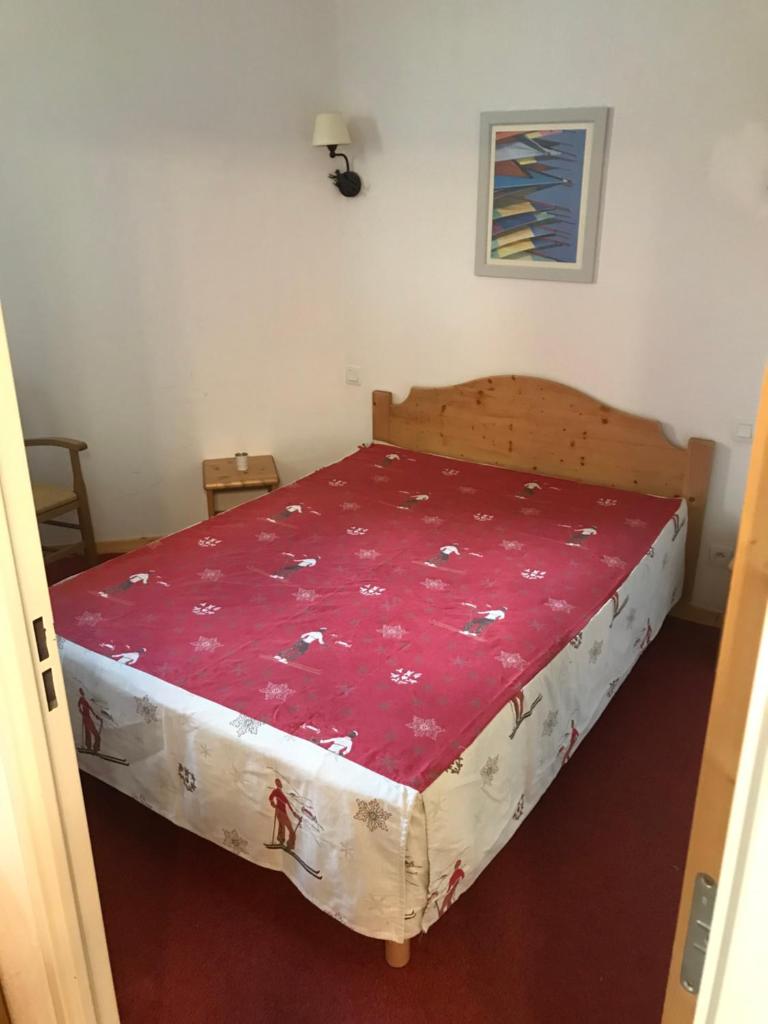 une chambre avec un grand lit avec une couverture rouge dans l'établissement T2 skis aux pieds Les Terrasses de la Bergerie, à Orcières