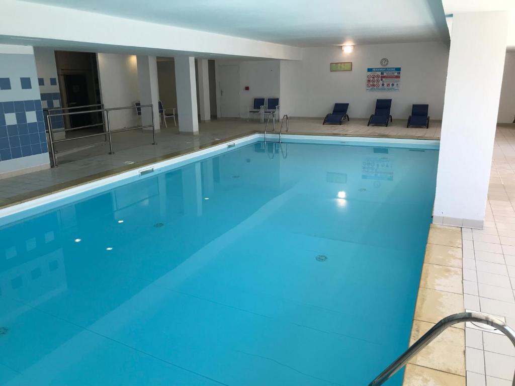 une grande piscine avec de l'eau bleue dans l'établissement T2 skis aux pieds Les Terrasses de la Bergerie, à Orcières 1 autre photo