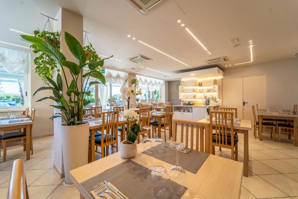 un restaurant avec des tables et des chaises et une cuisine dans l'établissement Melody Hotel, à Cervia