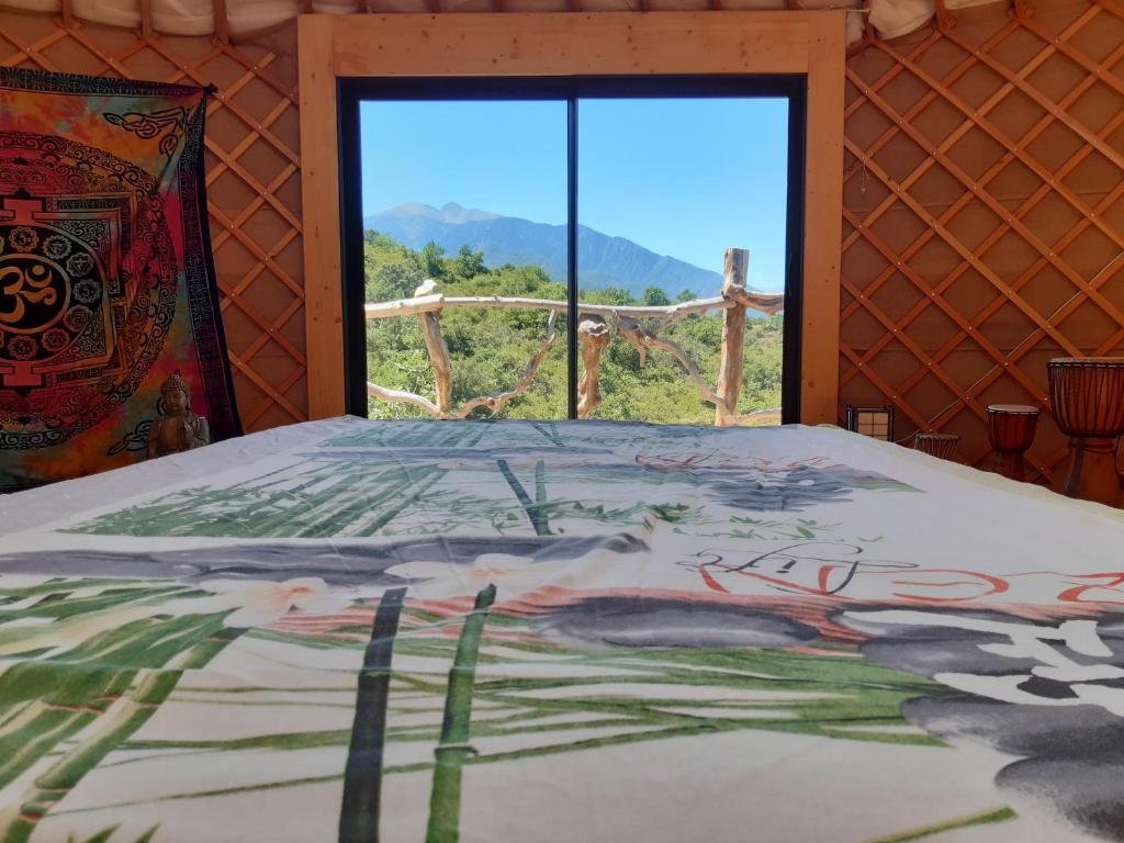 - une chambre avec un lit et une vue sur une fenêtre dans l'établissement Yourte contemporaine avec magnifique vue sur les montagnes, à Rigarda