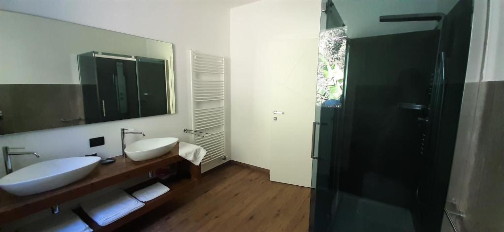 La salle de bains est pourvue de 2 lavabos, d'un miroir et d'une douche. dans l'établissement Villa Mari, à Dervio