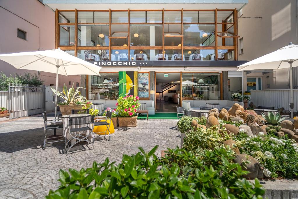 un bâtiment avec des tables, des chaises et des parasols dans l'établissement Hotel Pinocchio, à Cattolica