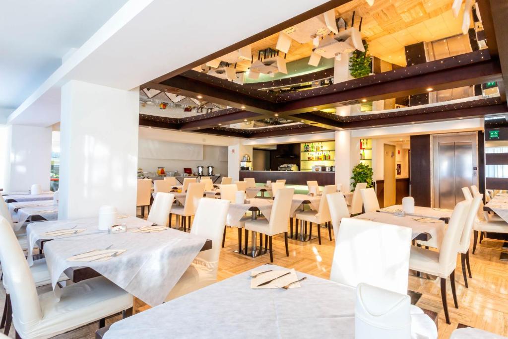 un restaurant avec des tables blanches et des chaises blanches dans l'établissement Hotel Petit Palais, sur le Lido de Venise