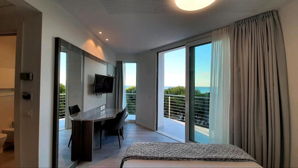 une chambre avec un lit et un bureau et un balcon dans l'établissement Grand Hotel Playa, à Lignano Sabbiadoro