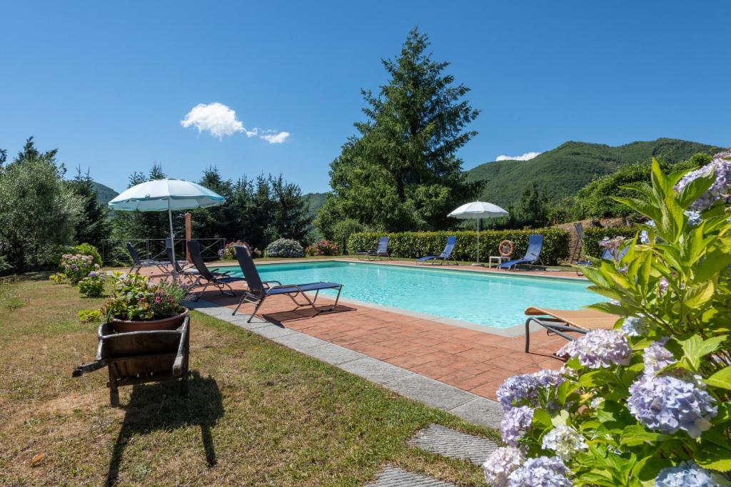 une piscine avec deux chaises et un parasol dans l'établissement Villa Popiglio by Mmega, à San Marcello Pistoiese