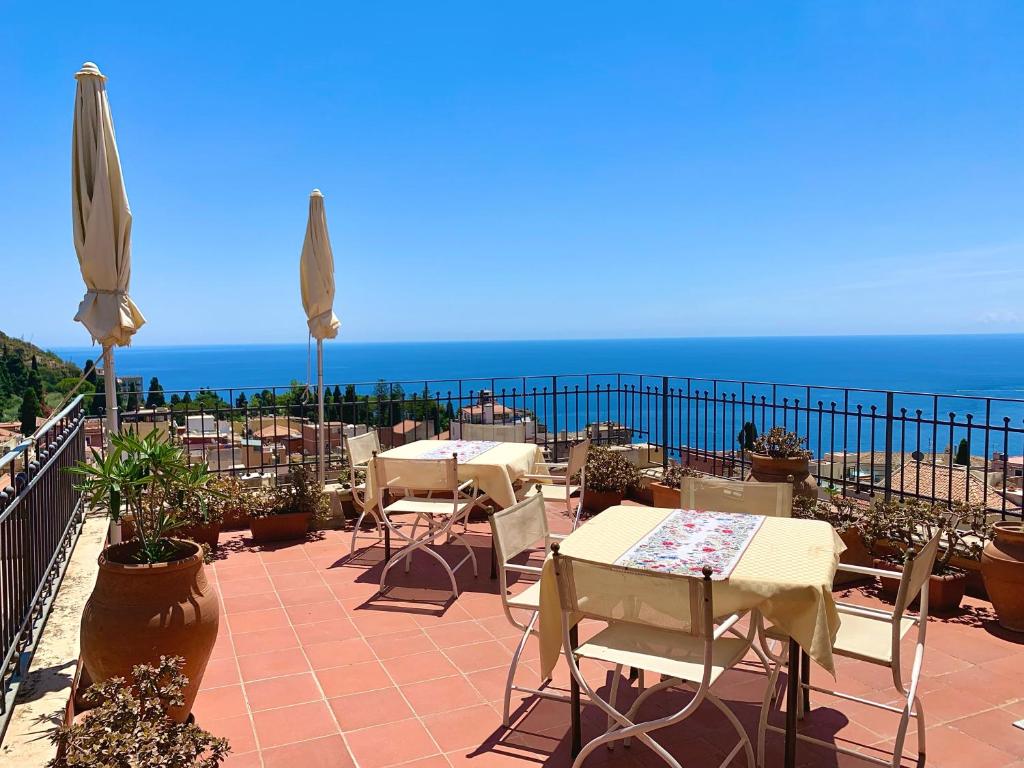une terrasse avec des tables et des chaises et l'océan dans l'établissement Hotel Isabella, à Taormine