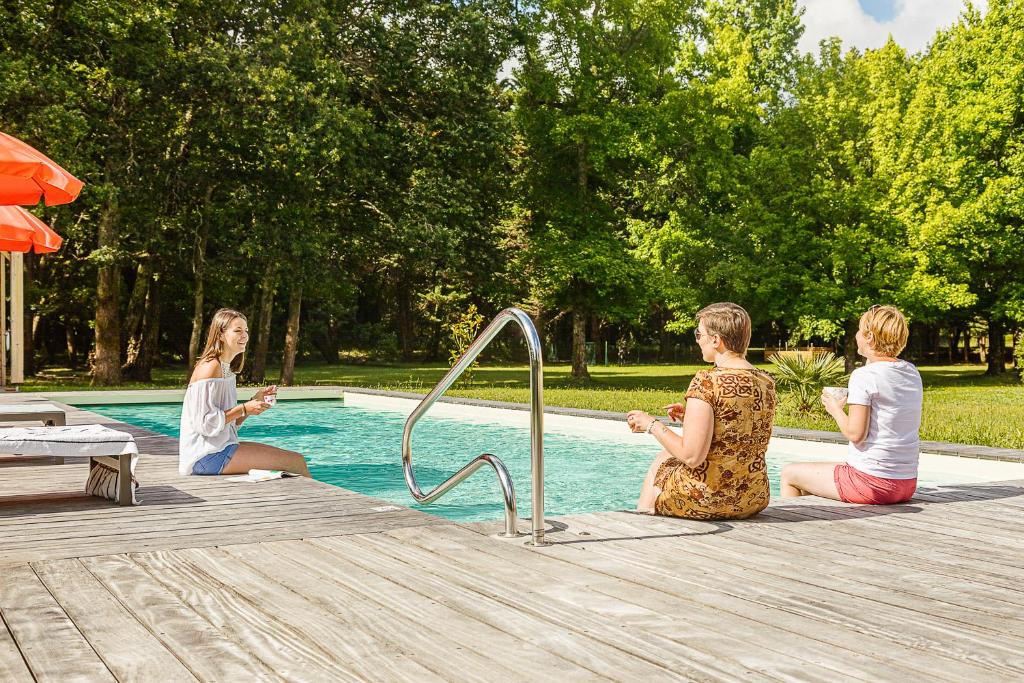- un groupe de femmes assises autour d'une piscine dans l'établissement Gites écolabellisés du Domaine de Ludeye - au calme dans le Médoc, à Listrac-Médoc