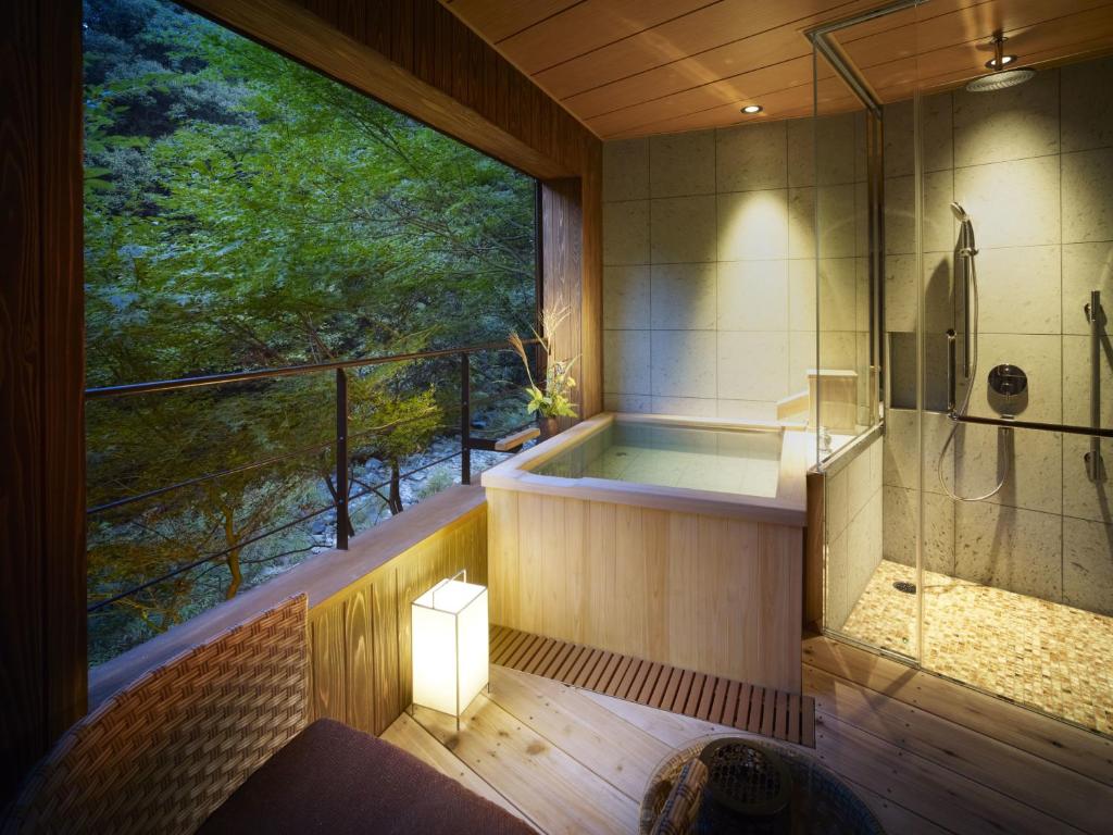 une baignoire dans une pièce avec une grande fenêtre dans l'établissement Fudoguchikan, à Izumi-Sano