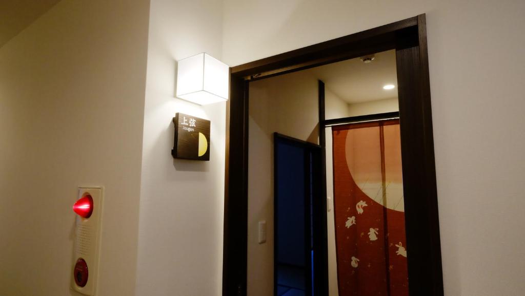 un couloir avec une porte et une lumière sur un mur dans l'établissement Oyado Tsukiusagi, à Miyajima