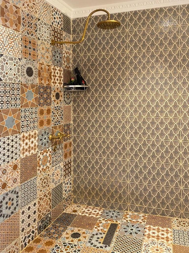La salle de bains est pourvue d'une douche et de carrelage sur le mur. dans l'établissement Riad Dar Yassine, à Marrakech