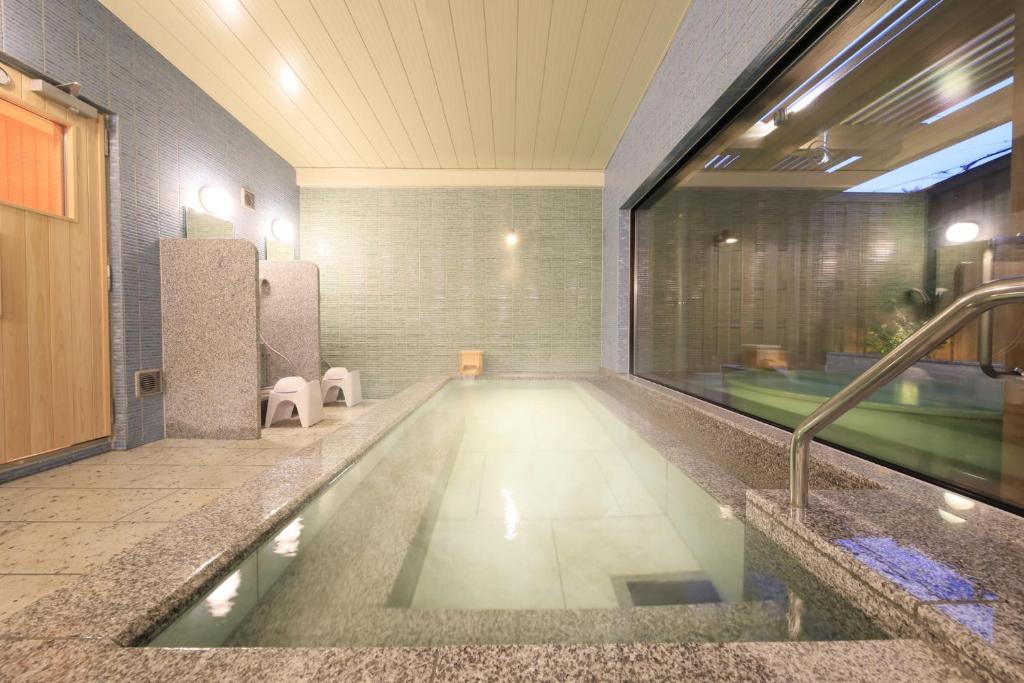 La salle de bains est pourvue d'une piscine et d'un lavabo. dans l'établissement KusatsuOnsen AeruyadoTakamatsu, à Kusatsu