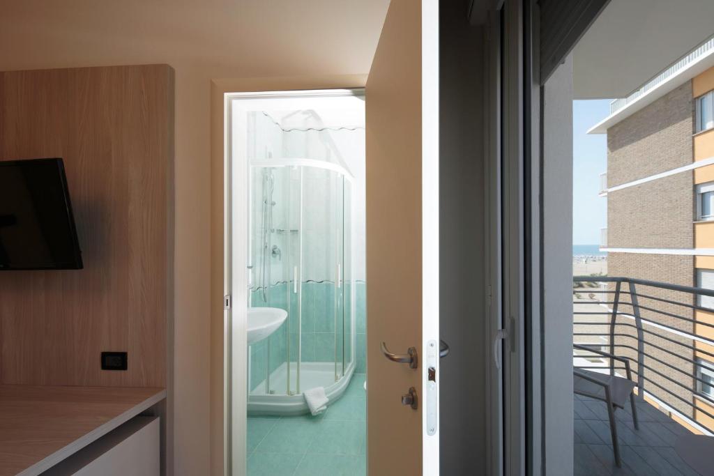 une salle de bains avec douche en verre et un balcon dans l'établissement Hotel Monaco, à Caorle