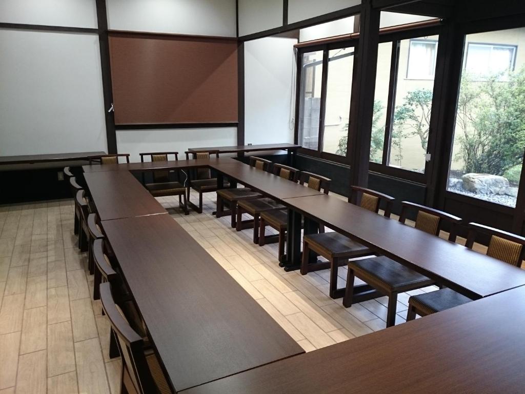 une salle de classe avec des tables, des chaises et des fenêtres en bois dans l'établissement Yumoto Onsen OharaSansou, à Kyoto