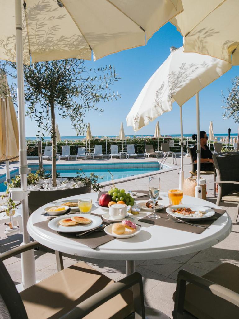 - une table avec des assiettes de nourriture à côté d'une piscine dans l'établissement Hotel Bristol, à Lido di Jesolo