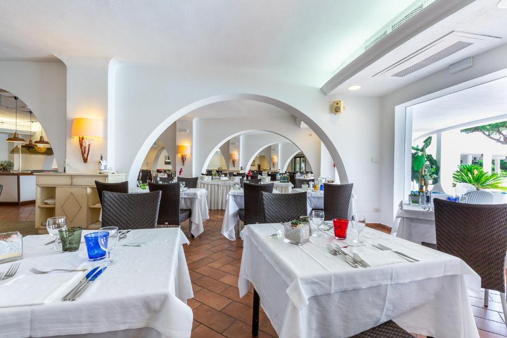 un restaurant avec deux tables à nappes blanches dans l'établissement Hotel Flamingo, à Santa Margherita di Pula