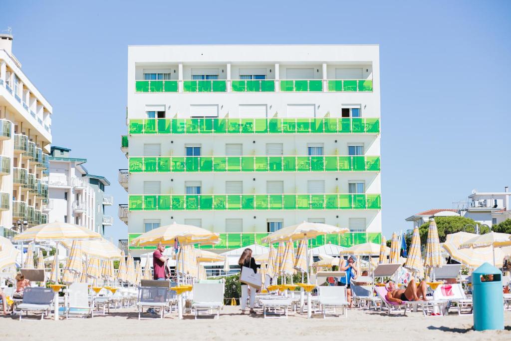 une plage avec des chaises et des parasols et un bâtiment dans l'établissement Hotel Bristol, à Lido di Jesolo