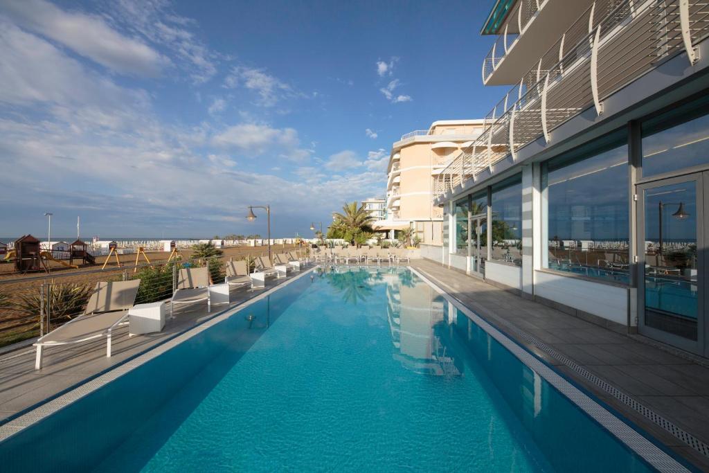 une piscine avec des chaises et un bâtiment dans l'établissement Hotel Delle Nazioni - Adults Only, à Caorle