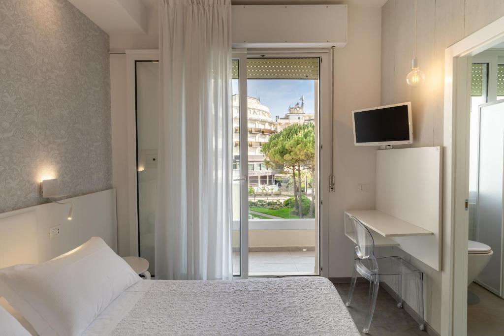 une chambre avec un lit, un bureau et une fenêtre dans l'établissement Hotel Majestic, à Milano Marittima