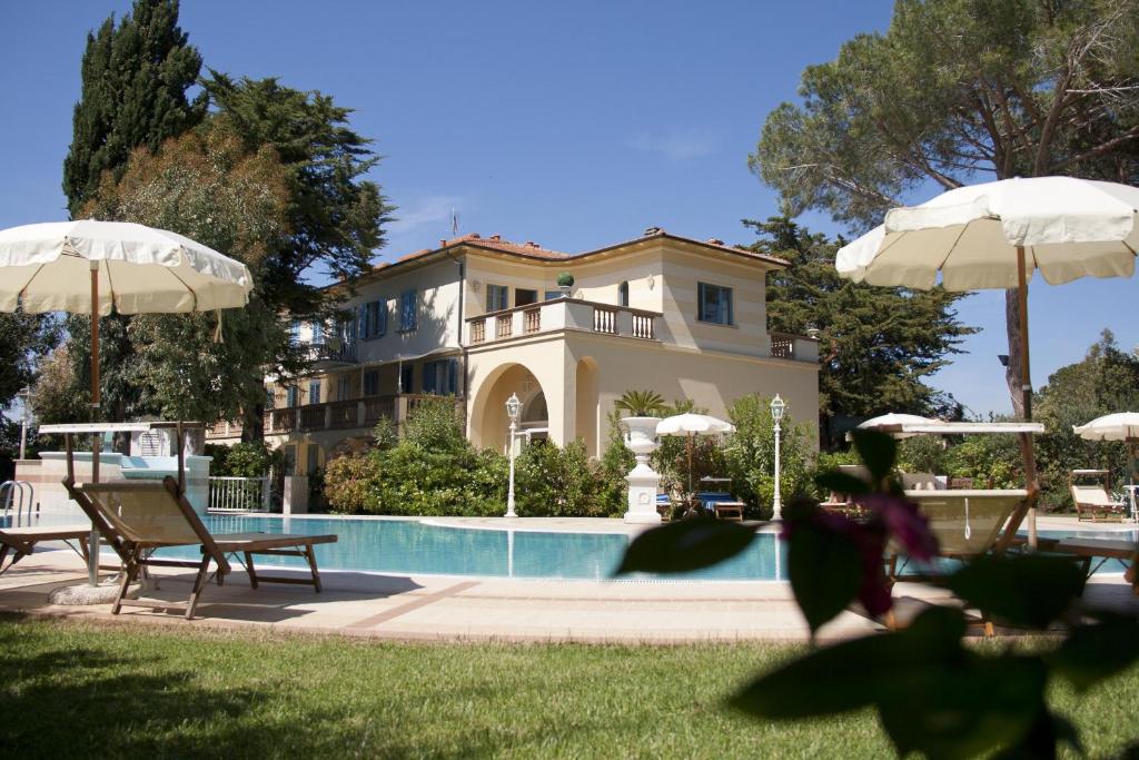 une maison avec une piscine et deux parasols dans l'établissement Villa Mazzanta Relais & Hotel, à Vada