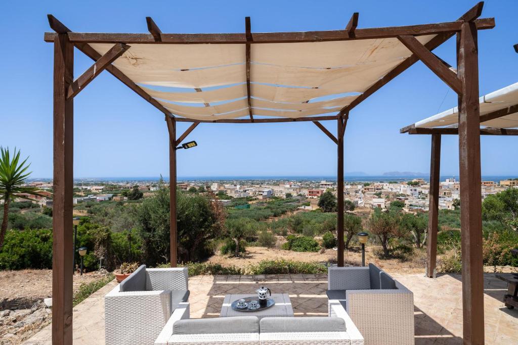 une pergola avec des chaises et une table sur une terrasse dans l'établissement Villa Sunrise Palm, à Marsala