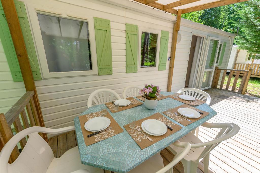 - une table et des chaises sur la terrasse couverte d'une maison dans l'établissement MOBIL HOME LE JACKSON 3, à Mirgaudon