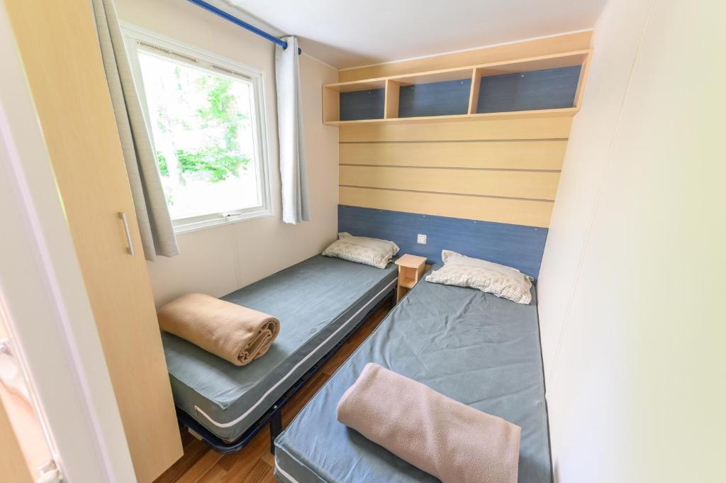 une petite chambre avec deux lits et une fenêtre dans l'établissement MOBIL HOME LE JACKSON 3, à Mirgaudon