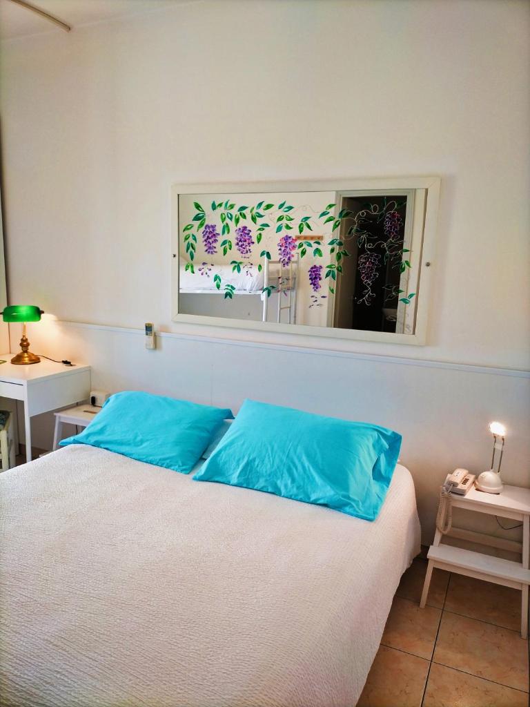 une chambre avec un lit avec des oreillers bleus et un miroir dans l'établissement Le Petit Hotel, à Lido di Jesolo