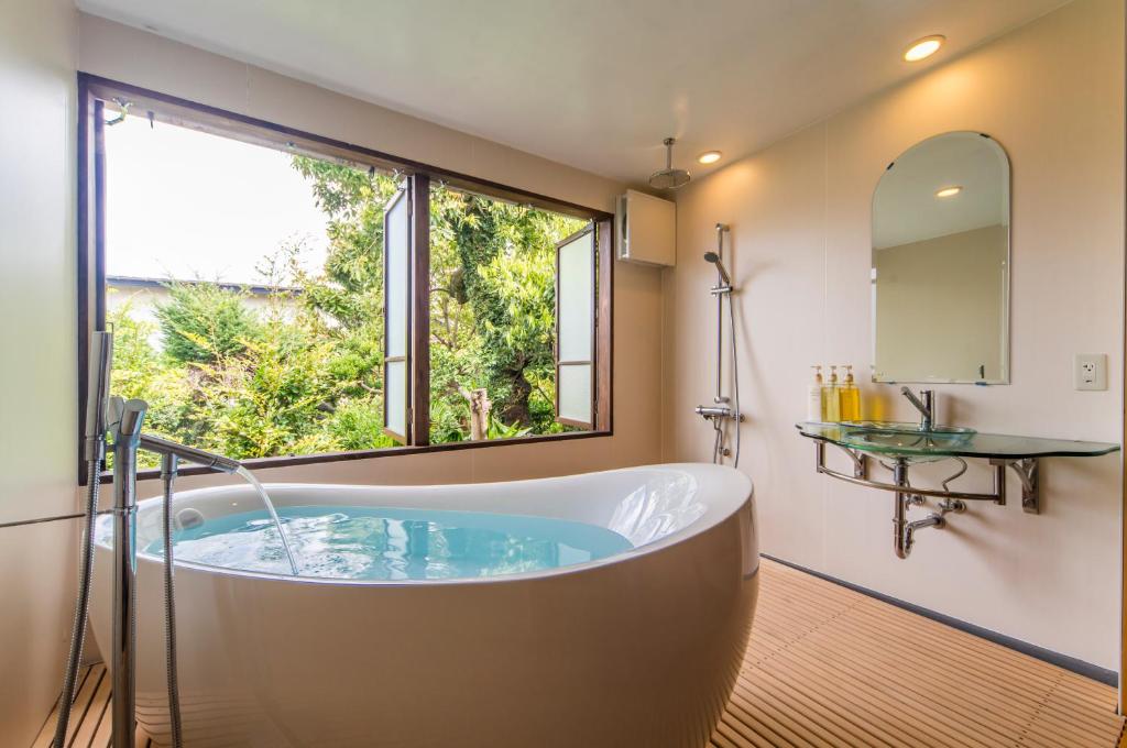 une baignoire dans une salle de bain avec une grande fenêtre dans l'établissement Kakujoro, à Tahara