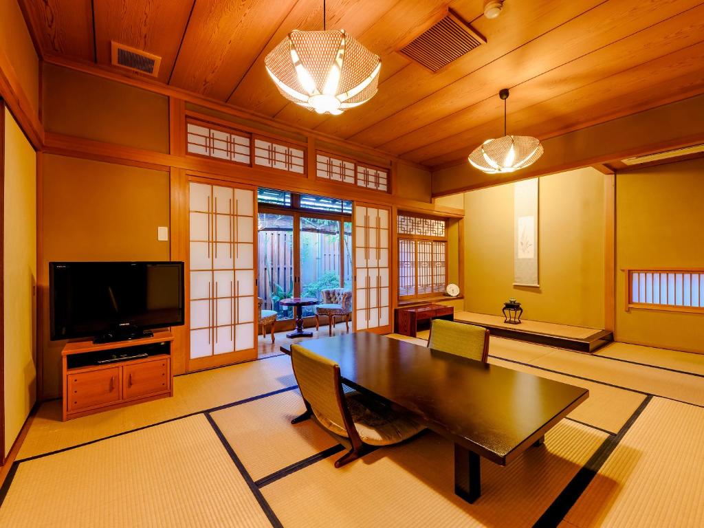 Il comprend un grand salon avec une table et une télévision. dans l'établissement Kappo Ryokan Yumesaki, à Beppu