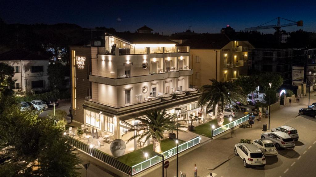 un bâtiment avec des voitures garées à l'extérieur le soir dans l'établissement Melody Hotel, à Cervia 33 autres photos