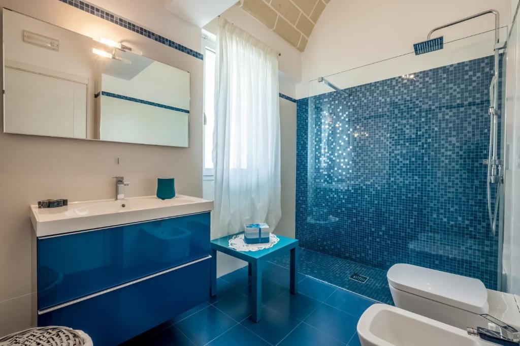 La salle de bains bleue est pourvue d'un lavabo et d'une douche. dans l'établissement Villa Bella Ostuni by Villa Plus, à Ostuni