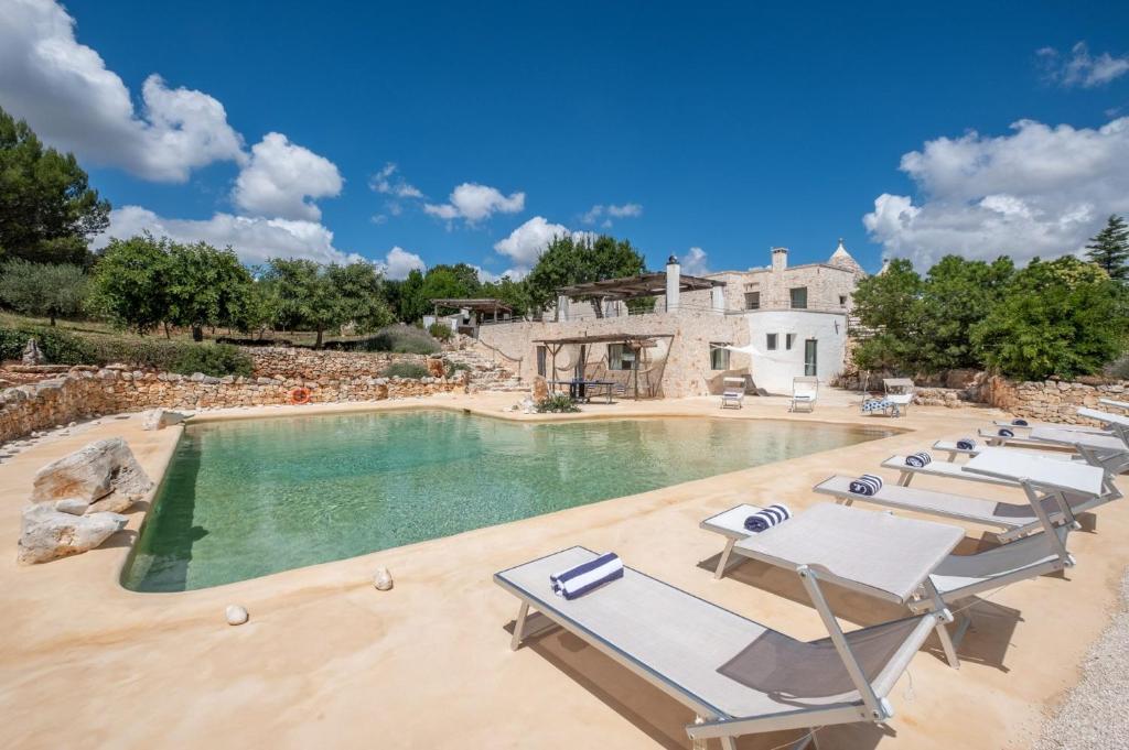 une piscine avec des chaises longues et une maison dans l'établissement Villa Trulli Laguna by Villa Plus, à Ostuni