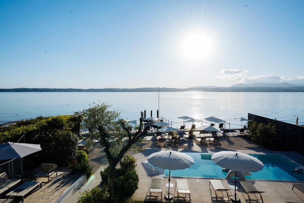 une vue sur une piscine avec des parasols et l'eau dans l'établissement AQVA Boutique Hotel (Adults Only), à Sirmione