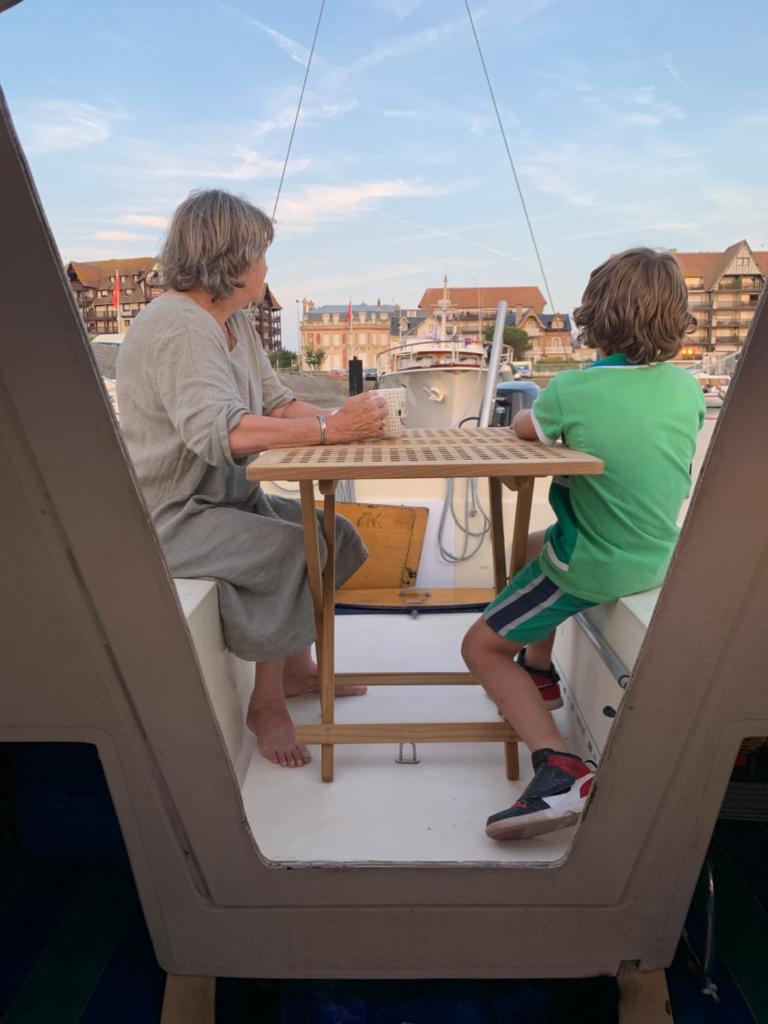 un homme et un enfant assis à une table sur un bateau dans l'établissement Madi au fil de l'eau à Deauville, à Deauville