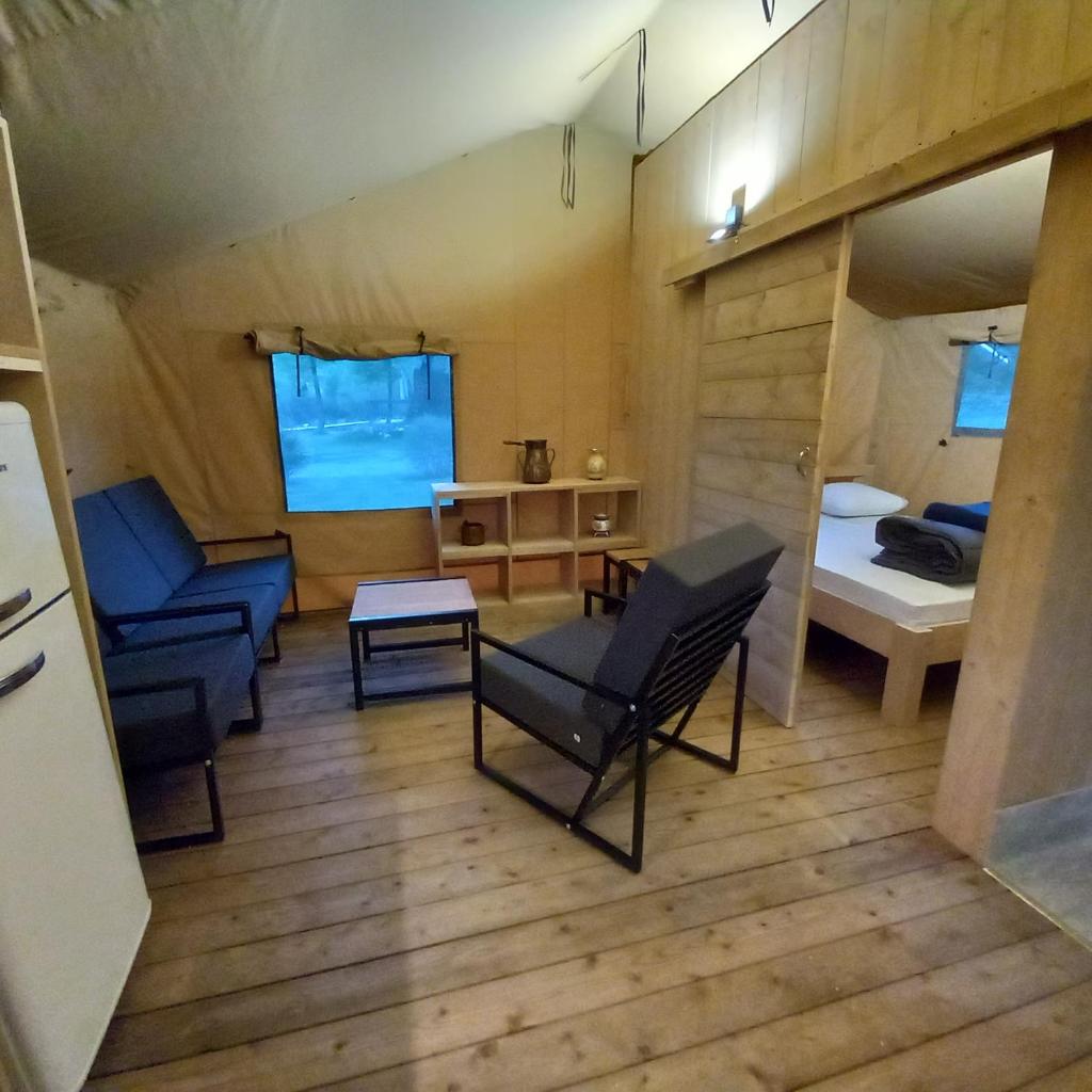 - une petite chambre avec un lit et des chaises dans l'établissement Camping du Moulin de Thoard, à Thoard