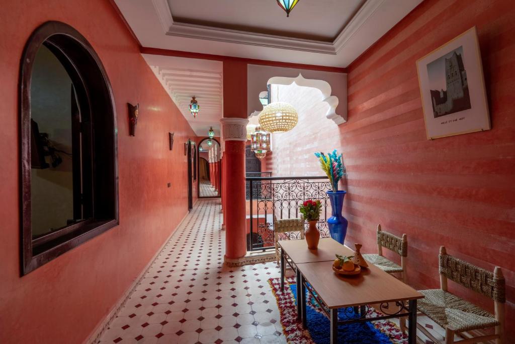 un couloir avec des murs rouges, une table et des chaises dans l'établissement Riad Haj Thami, à Marrakech