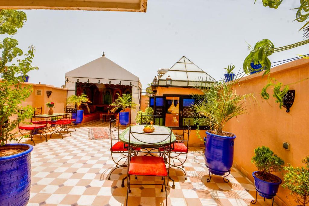 un patio avec une table, des chaises et des plantes en pot dans l'établissement Riad Haj Thami, à Marrakech