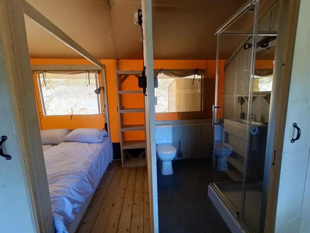 une petite chambre avec un lit et des toilettes dans l'établissement Tente Hula, à Colleville