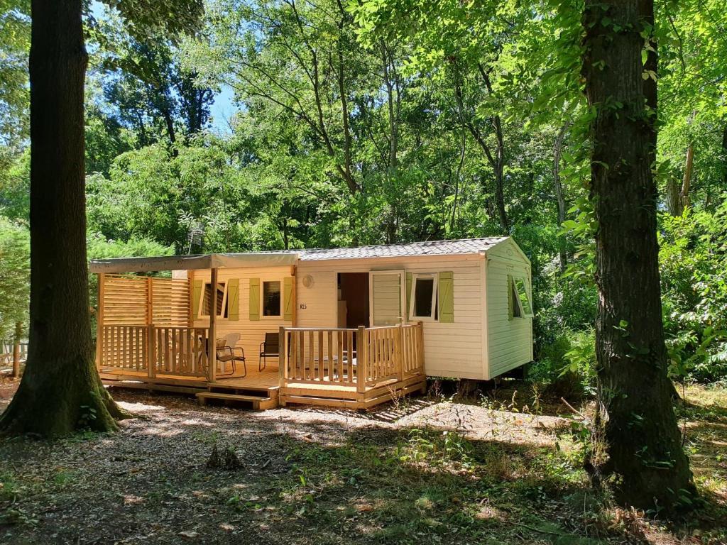 une petite cabine jaune dans les bois avec des arbres dans l'établissement Mobil-home le ROBINSON, à Mirgaudon 7 autres photos