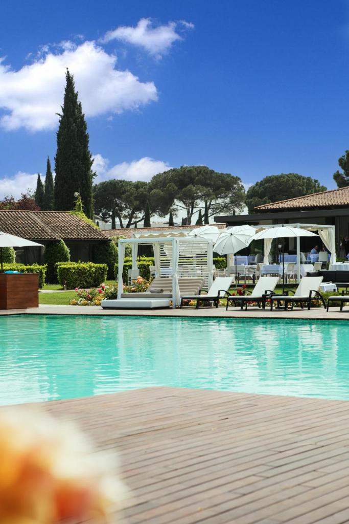 une grande piscine avec chaises et parasols dans l'établissement Splendido Bay Luxury Spa Resort, à Padenghe sul Garda