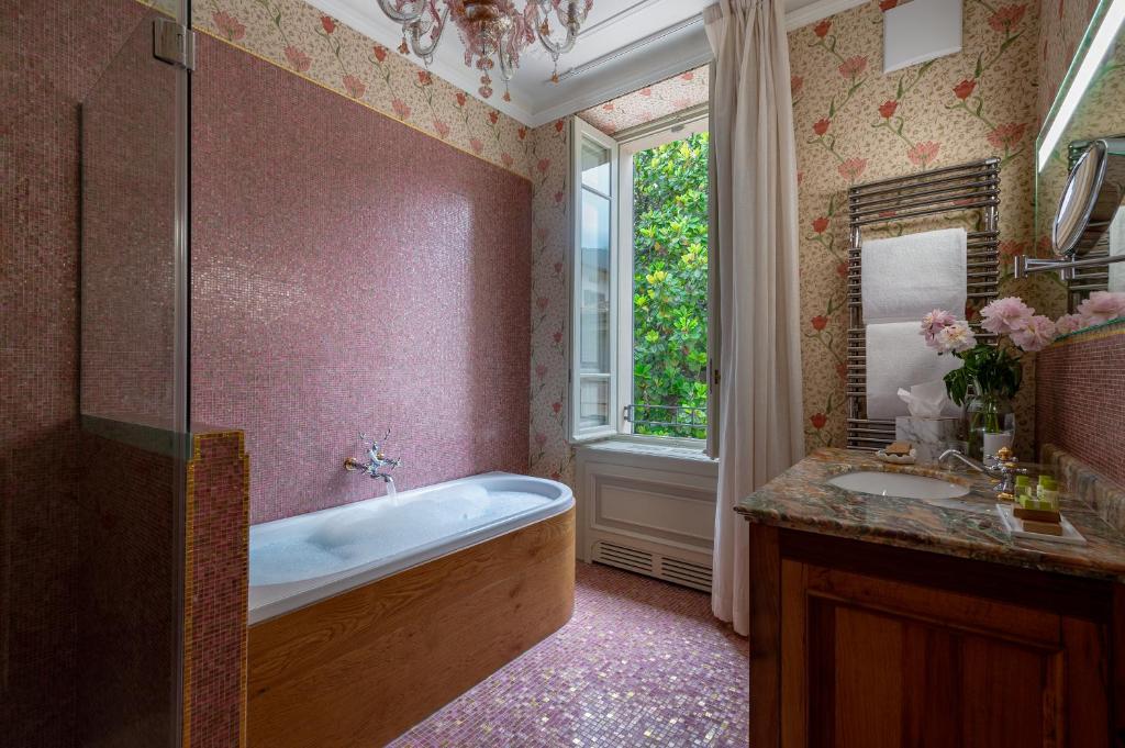 une salle de bain avec une baignoire, un lavabo et une fenêtre dans l'établissement Villa delle Palme, à Gargnano 57 autres photos