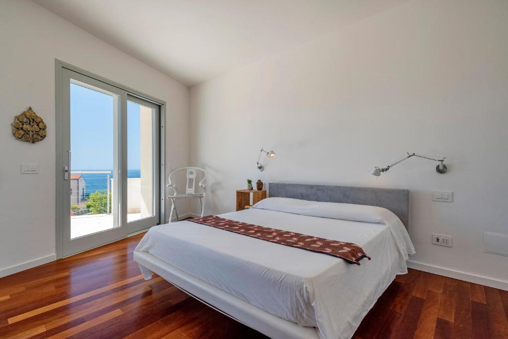 une chambre avec un grand lit et une grande fenêtre dans l'établissement Luxury Seafront Villa with Rooftop Pool & Stunning Sea Views, à Fertilia