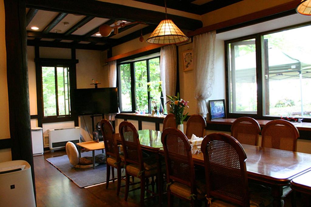 une salle à manger avec une table, des chaises et des fenêtres dans l'établissement Pension Marieペンションマリエ, à Yamanakako