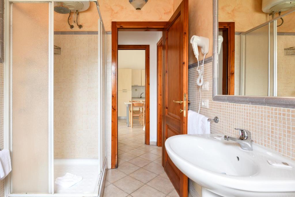 une salle de bain avec un lavabo, une douche et un miroir dans l'établissement Hotel Baia Del Porto, à Budoni