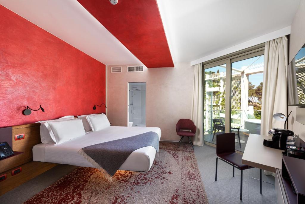 une chambre avec un grand lit et un mur rouge dans l'établissement Carrick Hotel Camogli Portofino Coast, à Camogli
