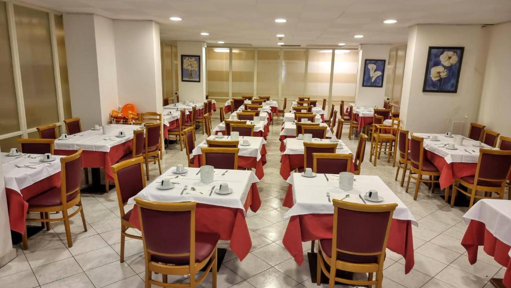 une salle à manger avec des tables et des chaises blanches dans l'établissement Hotel Regina, à Lignano Sabbiadoro 37 autres photos