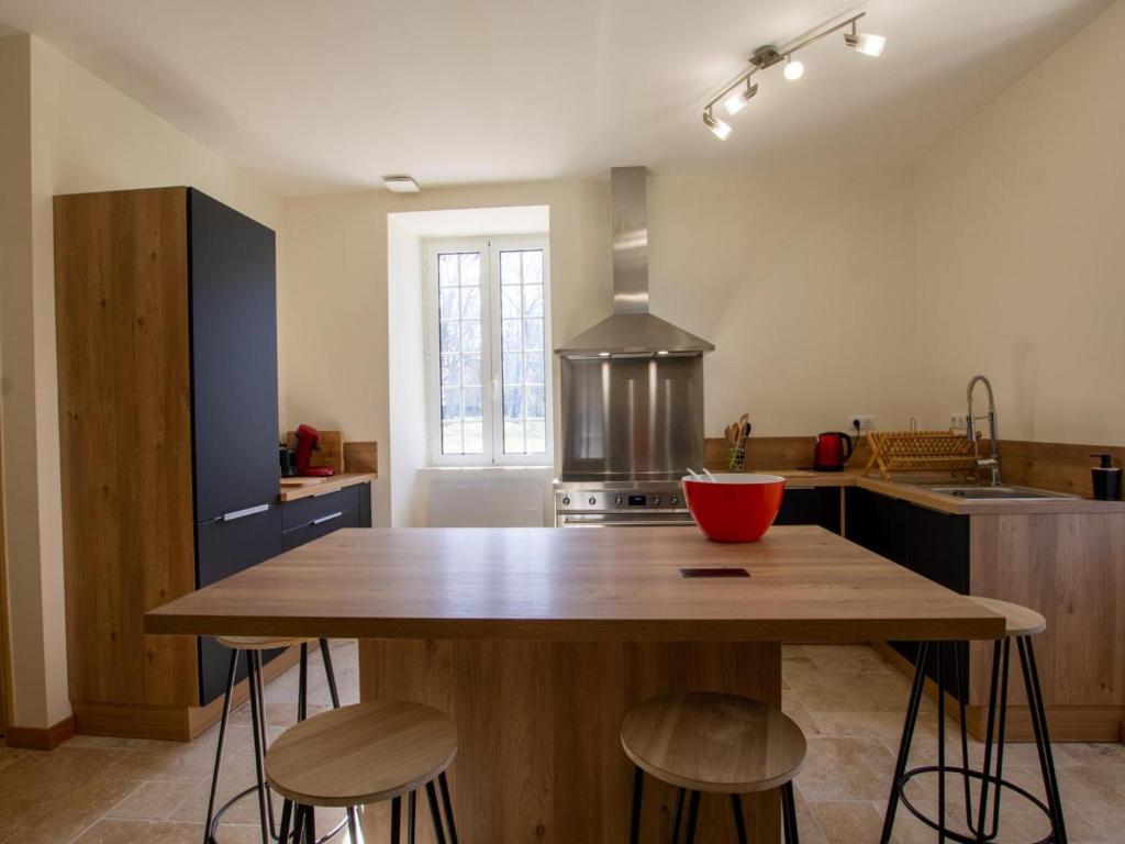 - une cuisine avec une table en bois et quelques tabourets dans l'établissement Grande maison rénovée avec piscine privée et parc, idéale pour vacances en famille en Dordogne - FR-1-616-216, à Savignac-les-Églises