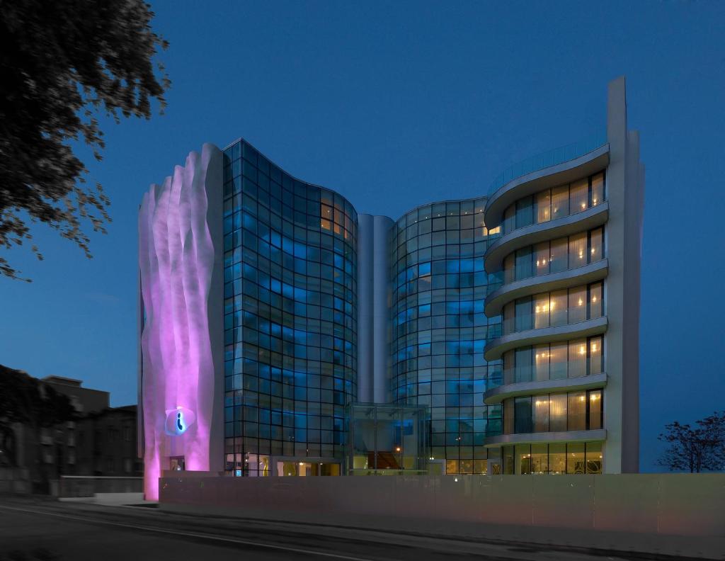 un grand bâtiment avec une façade violette la nuit dans l'établissement i-Suite Hotel, à Rimini